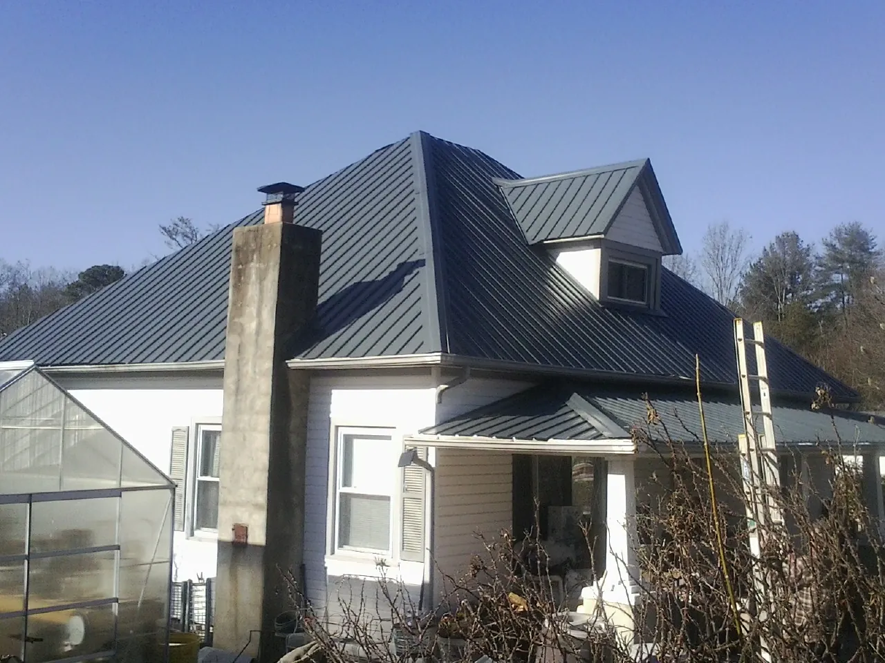 Dark blue standing seam metal roof on a white farmhouse with dormer — Slate & Tile Roof Repair by Roofing Brothers in Nicasio