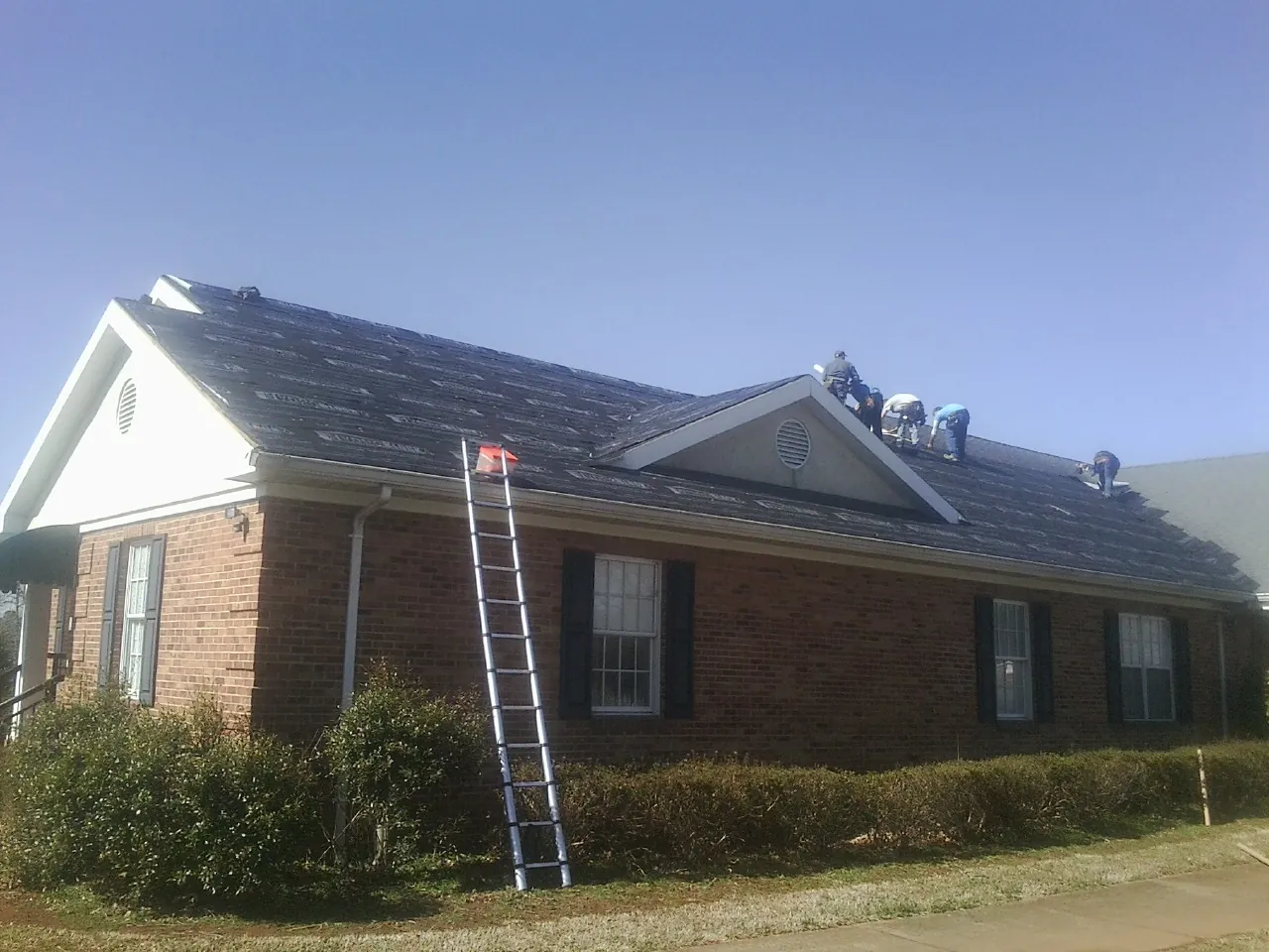 Crew tearing shingles off a brick ranch roof with a ladder set — Metal Roof Repair work by our crew in Nicasio