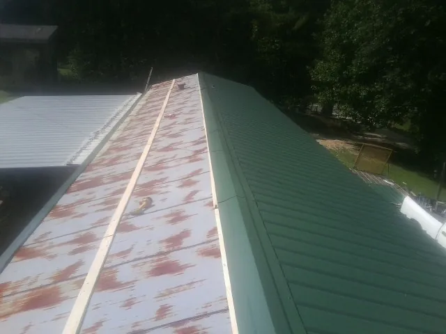 Old rusted panels beside newly installed green metal roofing — Wind Damage Roof Repair by Roofing Brothers in Nicasio