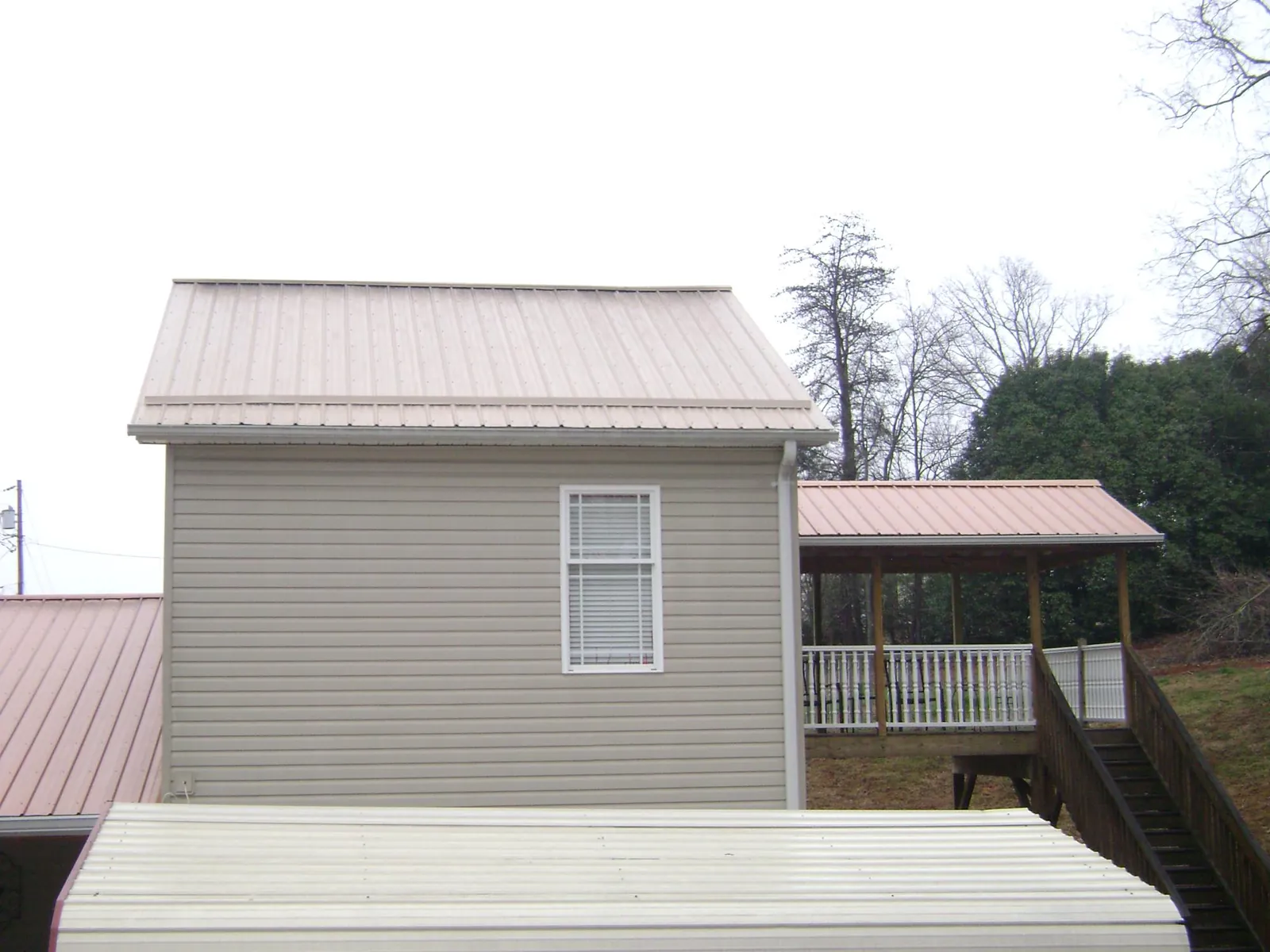 Tan metal roofs on a two story addition and attached porch, from a Roof Replacement job in Nicasio